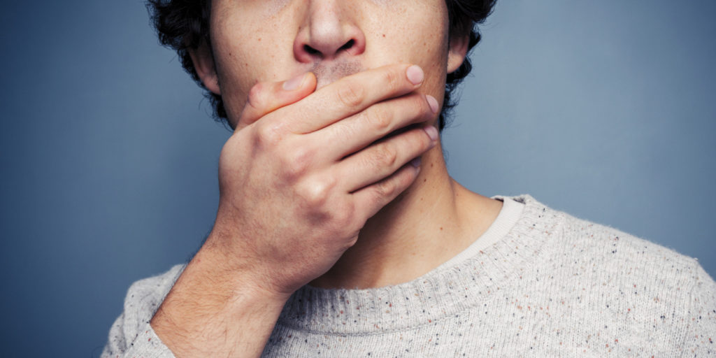 Shocked young man covering his mouth